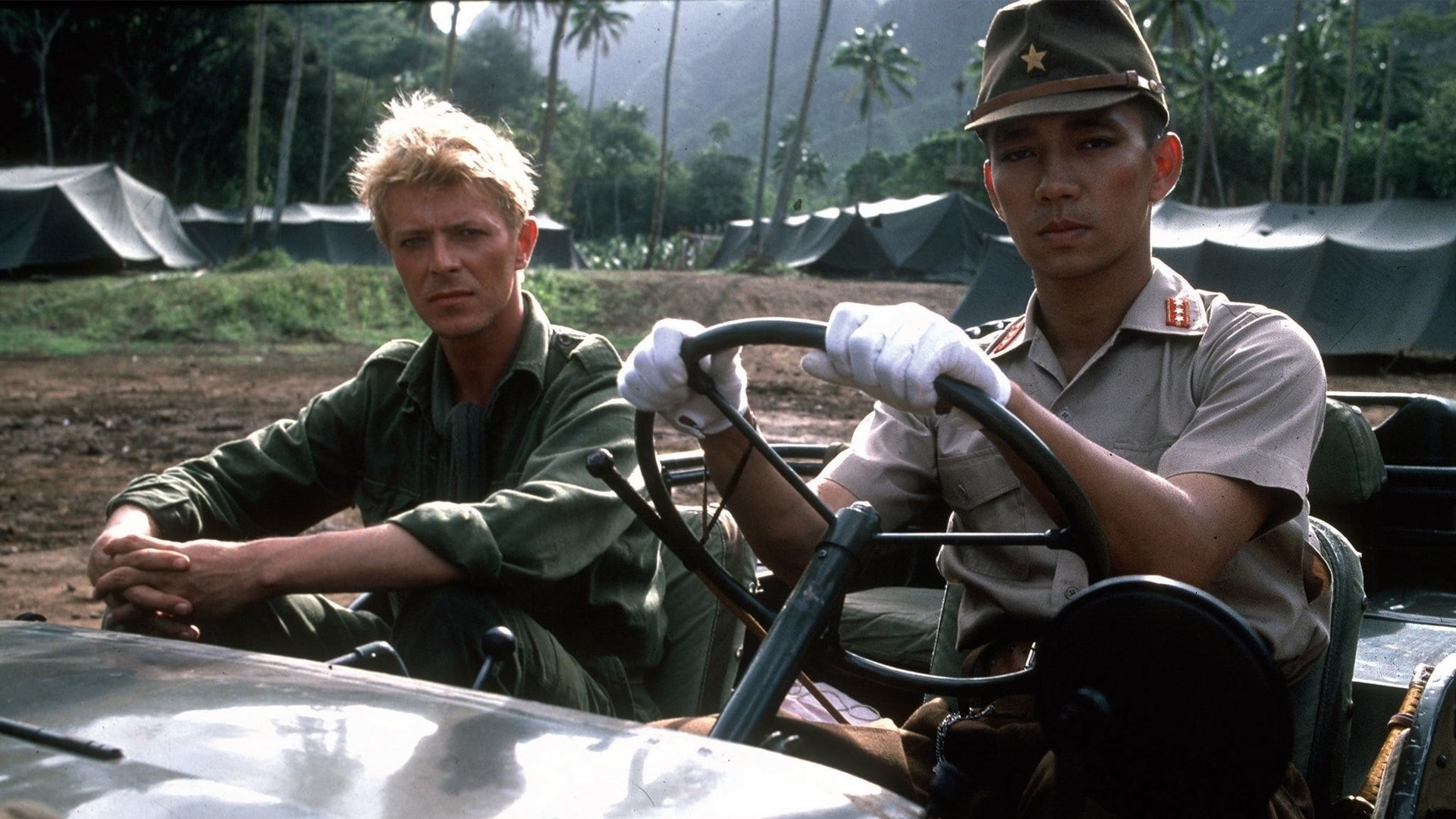 Cinematic background from Merry Christmas Mr. Lawrence 1983 - Island of Java, 1942, during World War II. British Major Jack Celliers arrives at a Japanese prison camp, run by the strict Captain Yonoi. Colonel John Lawrence, who has a profound knowledge of Japanese culture, and Sergeant Hara, brutal and simpleton, will witness the struggle of wills between two men from very different backgrounds who are tragically destined to clash.