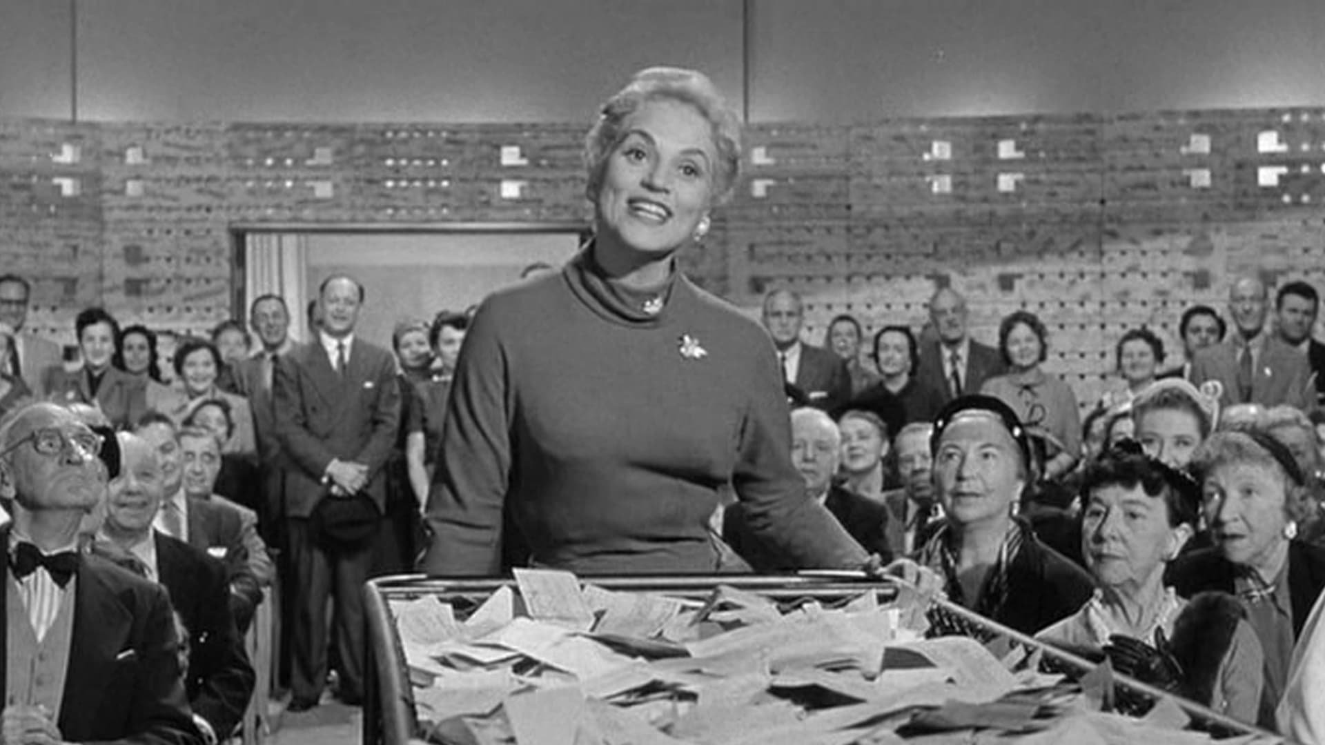 Cinematic background from The Solid Gold Cadillac 1956 - Laura Partridge is a very enthusiastic small stockholder of 10 shares in International Projects, a large corporation based in New York. She attends her first stockholder meeting ready to question the board of directors from their salaries to their operations.