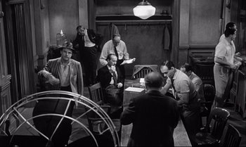 Movie still from “12 Angry Men” (1957), directed by Sidney Lumet – A black and white photo of a group of men sitting around a table; Wide shot, High angle