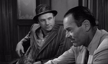 Movie still from “12 Angry Men” (1957), directed by Sidney Lumet – Two men are sitting on a couch and one is wearing a hat; Close Up shot, Over the shoulder angle