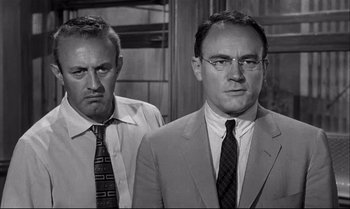 Movie still from “12 Angry Men” (1957), directed by Sidney Lumet – Two men standing next to each other in front of a wall; Close Up shot, Over the shoulder angle