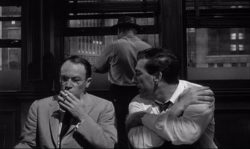 Movie still from “12 Angry Men” (1957), directed by Sidney Lumet – A couple of men sitting next to each other on top of a train; Medium shot, Over the shoulder angle