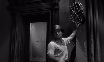 Movie still from “12 Angry Men” (1957), directed by Sidney Lumet – A black and white photo of a man holding a metal object; Medium shot, Low angle