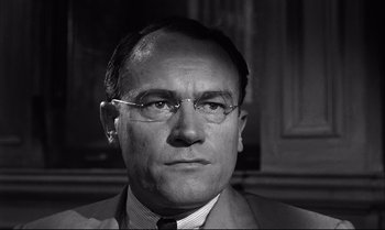 Movie still from “12 Angry Men” (1957), directed by Sidney Lumet – An older man wearing glasses and a suit; Close Up shot, Low angle