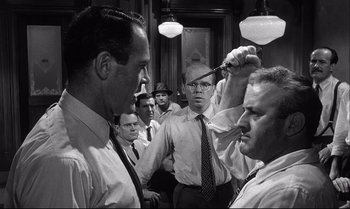 Movie still from “12 Angry Men” (1957), directed by Sidney Lumet – A group of men standing next to each other in a room; Medium shot, Over the shoulder angle