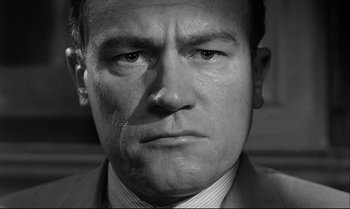 Movie still from “12 Angry Men” (1957), directed by Sidney Lumet – Black and white photograph of a man in a suit smoking a cigarette; Close Up shot, Low angle