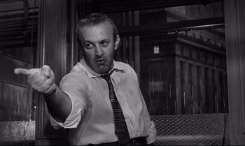Movie still from “12 Angry Men” (1957), directed by Sidney Lumet – A black and white photo of a man in a suit and tie; Close Up shot, Low angle