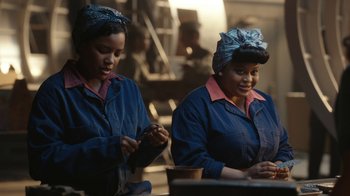 Movie still from “A League of Their Own” (2022), created by Abbi Jacobson – A couple of women standing next to each other in a room; Medium shot, Over the shoulder angle