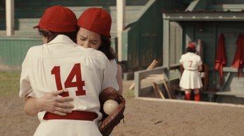Movie still from “A League of Their Own” (2022), created by Abbi Jacobson – A couple of people that are hugging each other; Medium shot, Over the shoulder angle