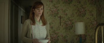 Movie still from “Hateship Loveship” (2013), directed by Liza Johnson – A woman holding a bowl while standing next to a wall; Medium shot, Over the shoulder angle