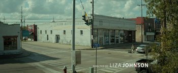 Movie still from “Hateship Loveship” (2013), directed by Liza Johnson – A view of a street corner from across the street; Extreme Wide shot, Low angle