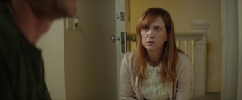 Movie still from “Hateship Loveship” (2013), directed by Liza Johnson – A woman sitting in front of a door looking sad; Medium shot, Over the shoulder angle