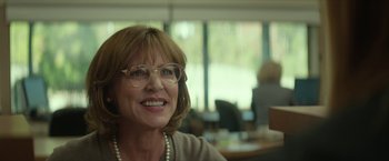 Movie still from “Hateship Loveship” (2013), directed by Liza Johnson – An older woman wearing glasses and smiling for the camera; Close Up shot, Over the shoulder angle
