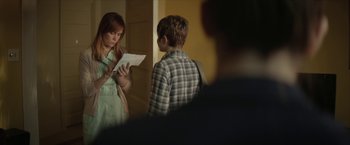 Movie still from “Hateship Loveship” (2013), directed by Liza Johnson – A woman and a boy standing next to each other holding papers; Medium shot, Over the shoulder angle