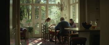 Movie still from “Hateship Loveship” (2013), directed by Liza Johnson – A group of people sitting at a table in front of a window; Wide shot, Over the shoulder angle