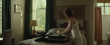 Movie still from “Hateship Loveship” (2013), directed by Liza Johnson – A woman is opening a suitcase in a bedroom; Medium shot, Over the shoulder angle