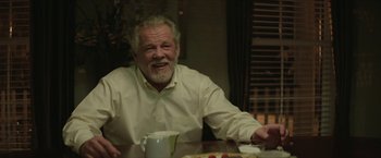 Movie still from “Hateship Loveship” (2013), directed by Liza Johnson – An older man sitting at a table with food; Close Up shot, Over the shoulder angle