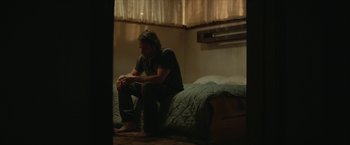 Movie still from “Hateship Loveship” (2013), directed by Liza Johnson – A man sitting on a bed in a room; Wide shot, Over the shoulder angle