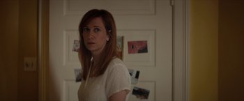Movie still from “Hateship Loveship” (2013), directed by Liza Johnson – A woman with red hair standing in front of a white wall; Close Up shot, Over the shoulder angle