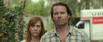 Movie still from “Hateship Loveship” (2013), directed by Liza Johnson – A man and a woman standing next to each other in front of trees; Close Up shot, Low angle