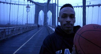 Movie still from “He Got Game” (1998), directed by Spike Lee – A man standing on a bridge holding a basketball; Close Up shot, Low angle