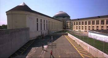 Movie still from “He Got Game” (1998), directed by Spike Lee – An empty parking lot in front of a large building; Extreme Wide shot, High angle