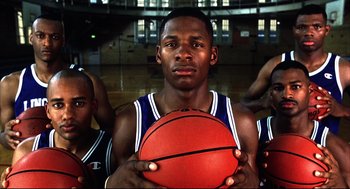 Movie still from “He Got Game” (1998), directed by Spike Lee – A man holding a basketball in front of a group of other men; Close Up shot, Low angle
