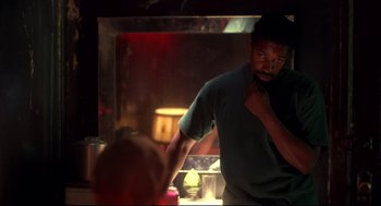 Movie still from “He Got Game” (1998), directed by Spike Lee – A man standing next to a fireplace in a dark room; Medium shot, Low angle