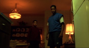 Movie still from “He Got Game” (1998), directed by Spike Lee – Two young men standing in a living room in front of a lamp; Medium shot, Low angle