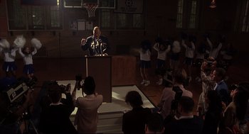 Movie still from “He Got Game” (1998), directed by Spike Lee – A man is speaking at a podium in front of a group of people; Wide shot, Low angle