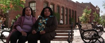 Movie still from “He's Just Not That Into You” (2009), directed by Ken Kwapis – Two women sitting on a bench in front of a brick building; Medium shot, High angle