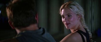 Movie still from “He's Just Not That Into You” (2009), directed by Ken Kwapis – A young woman smiles at the camera as a man sits in the background; Close Up shot, Over the shoulder angle