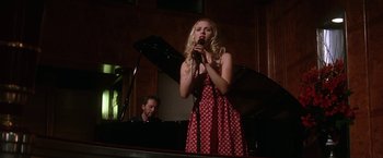 Movie still from “He's Just Not That Into You” (2009), directed by Ken Kwapis – A woman in a polka dot dress singing into a microphone while a man plays piano; Medium shot, Low angle