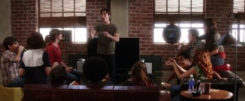 Movie still from “He's Just Not That Into You” (2009), directed by Ken Kwapis – A man standing in front of a group of people in a room; Wide shot, Over the shoulder angle
