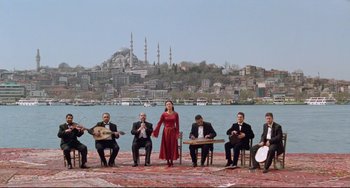 Movie still from “Head-On” (2004), directed by Fatih Akin – A group of men and women sitting around a woman; Extreme Wide shot, Low angle