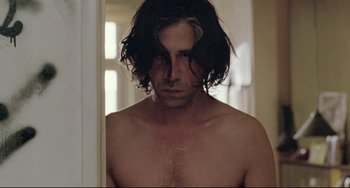 Movie still from “Head-On” (2004), directed by Fatih Akin – A man with long black hair looking into a bathroom mirror; Close Up shot, Low angle
