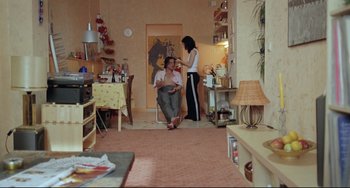 Movie still from “Head-On” (2004), directed by Fatih Akin – A man sitting on a chair next to a woman in a living room; Wide shot, High angle