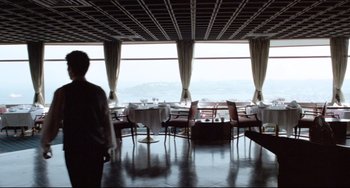 Movie still from “Head-On” (2004), directed by Fatih Akin – A person standing in a room with a view of a mountain; Extreme Wide shot, Low angle