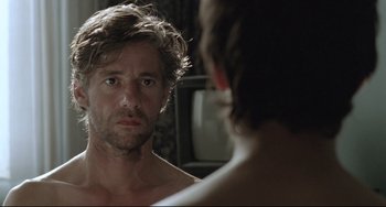 Movie still from “Head-On” (2004), directed by Fatih Akin – A man looking at himself in the mirror in front of a television; Close Up shot, Over the shoulder angle