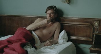 Movie still from “Head-On” (2004), directed by Fatih Akin – A shirtless man sitting in a bed next to a wall; Medium shot, High angle