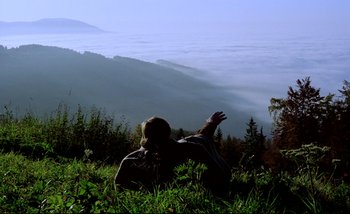 Movie still from “Heart of Glass” (1976), directed by Werner Herzog – A man laying in the grass on top of a hill; Extreme Wide shot, Low angle