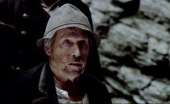 Movie still from “Heart of Glass” (1976), directed by Werner Herzog – An older man wearing a hat and a jacket; Close Up shot, Low angle