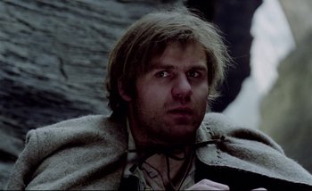 Movie still from “Heart of Glass” (1976), directed by Werner Herzog – A person wearing a cape and looking at the camera; Close Up shot, Low angle