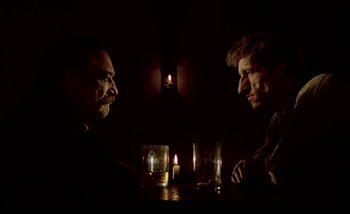 Movie still from “Heart of Glass” (1976), directed by Werner Herzog – Two men sitting at a table with candles in front of them; Close Up shot, Low angle