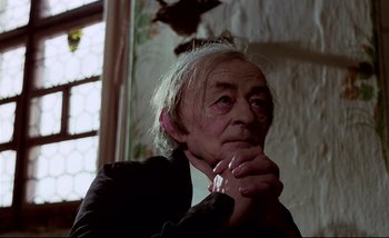 Movie still from “Heart of Glass” (1976), directed by Werner Herzog – An older man is sitting in front of a window; Close Up shot, Low angle