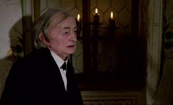 Movie still from “Heart of Glass” (1976), directed by Werner Herzog – An older man in a suit and tie looking to his left; Close Up shot, Over the shoulder angle