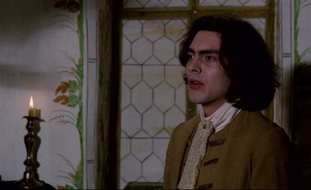 Movie still from “Heart of Glass” (1976), directed by Werner Herzog – A man with long black hair wearing a brown jacket; Medium shot, Low angle