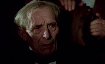 Movie still from “Heart of Glass” (1976), directed by Werner Herzog – An old man in a black suit and white bow tie; Close Up shot, Over the shoulder angle