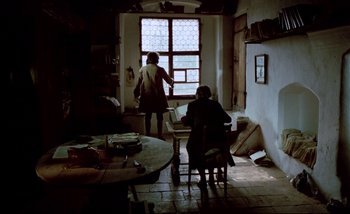 Movie still from “Heart of Glass” (1976), directed by Werner Herzog – Two people are sitting in a room looking out a window; Wide shot, Low angle
