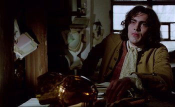Movie still from “Heart of Glass” (1976), directed by Werner Herzog – A man sitting at a table with a plate of food in front of him; Medium shot, Low angle